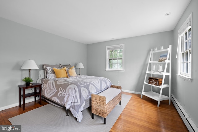 bedroom featuring a baseboard radiator, wood finished floors, and baseboards