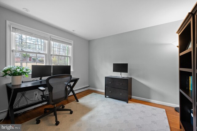 office space featuring light wood finished floors, baseboard heating, and baseboards