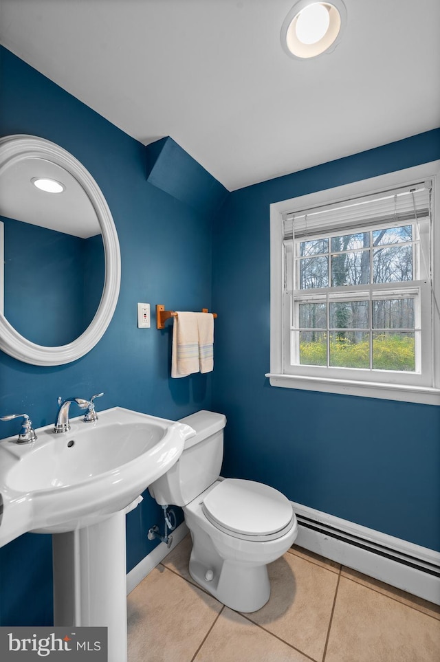 half bath with baseboard heating, baseboards, toilet, and tile patterned flooring