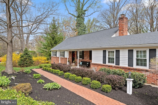 single story home with a chimney, a shingled roof, and brick siding