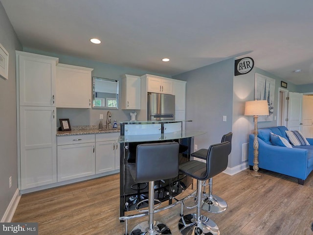 169 E Buckingham Dr, Rehoboth Beach, DE 19971 - kitchen with freestanding refrigerator, light wood-style flooring, white cabinetry, baseboards, and recessed lighting