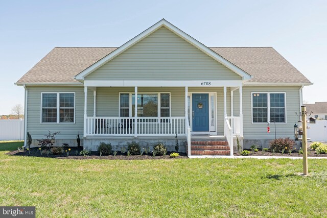 bungalow-style house with a front yard, covered porch, and roof with shingles