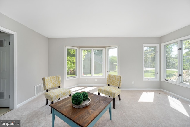 living area with visible vents, light colored carpet, and baseboards