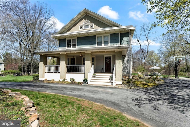 view of front facade featuring covered porch, stucco siding, and asphalt driveway