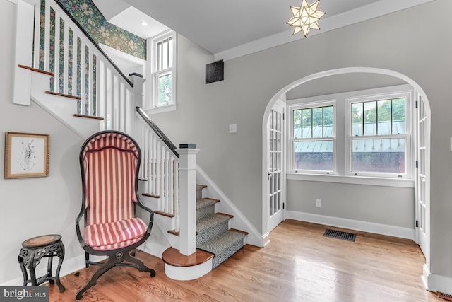 stairs featuring arched walkways, wood finished floors, and baseboards