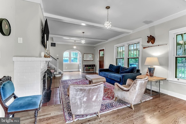 living area with wood finished floors, baseboards, beamed ceiling, arched walkways, and crown molding
