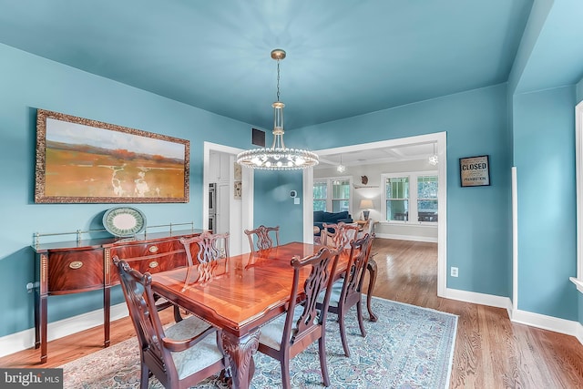 dining space featuring wood finished floors, baseboards, and a chandelier