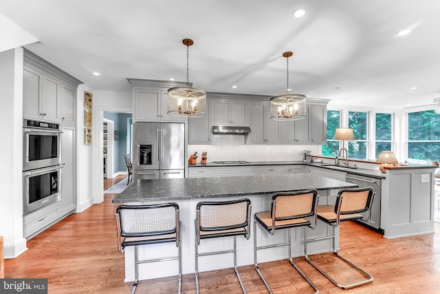kitchen featuring stainless steel appliances, gray cabinets, a sink, a chandelier, and tasteful backsplash