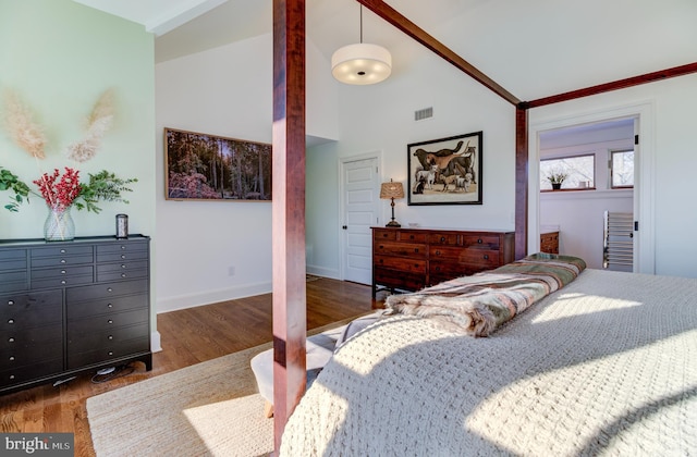 bedroom with wood finished floors, high vaulted ceiling, baseboards, and crown molding