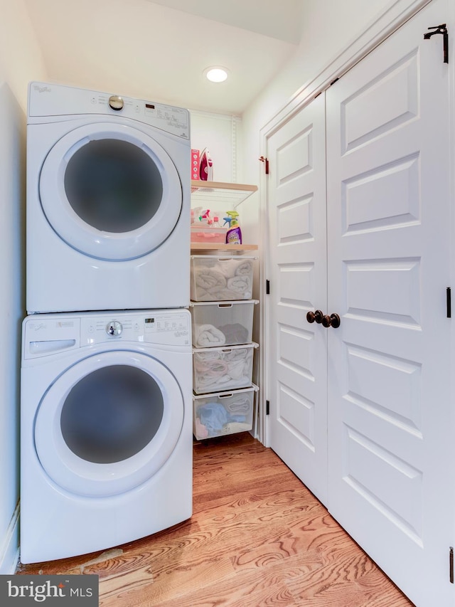 laundry area featuring stacked washing machine and dryer, wood finished floors, and recessed lighting