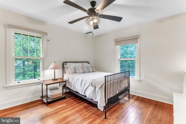 bedroom with baseboards, light wood-type flooring, and a ceiling fan