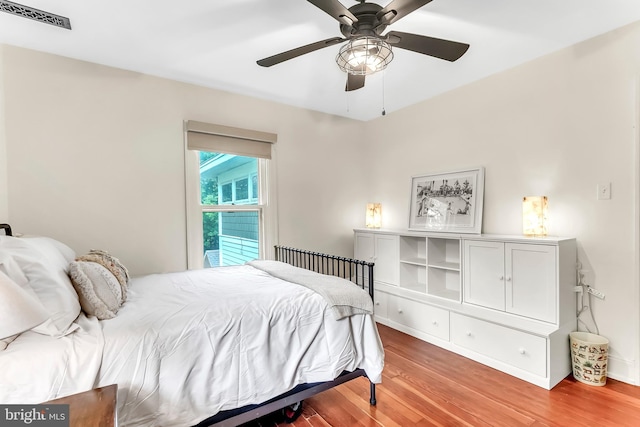 bedroom with light wood-style floors, a ceiling fan, and baseboards