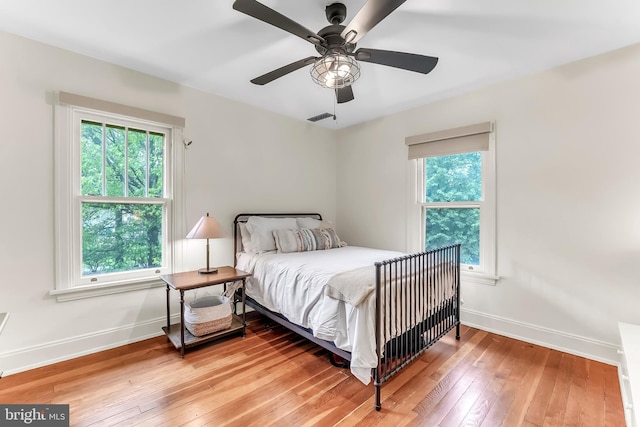 bedroom featuring baseboards, light wood-style floors, and ceiling fan