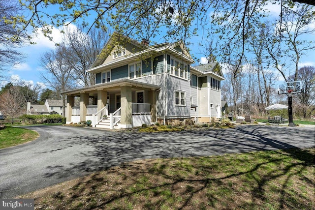 view of front of property featuring covered porch, driveway, and a chimney