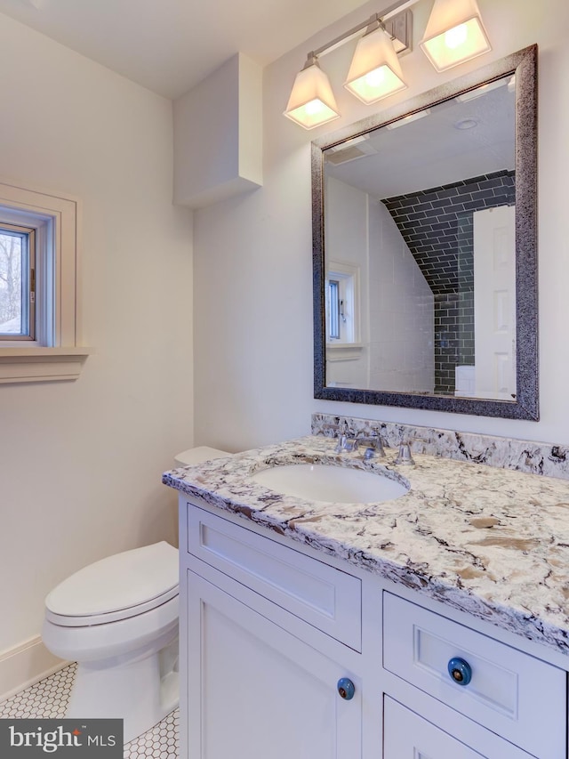 bathroom featuring toilet, vanity, tile patterned floors, and baseboards