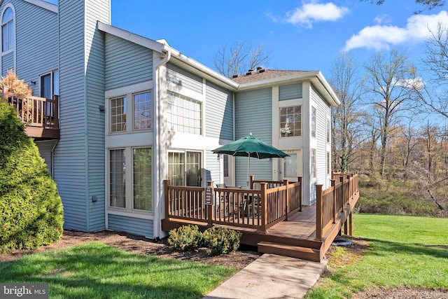 back of house featuring a deck, a lawn, and a chimney