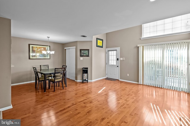 dining room with a chandelier, light wood finished floors, and baseboards