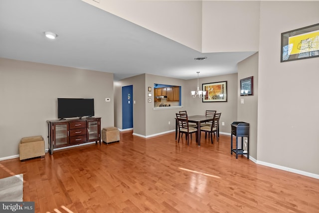 living area with a notable chandelier, light wood-style floors, and baseboards