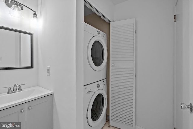 clothes washing area featuring stacked washer and dryer, laundry area, and a sink