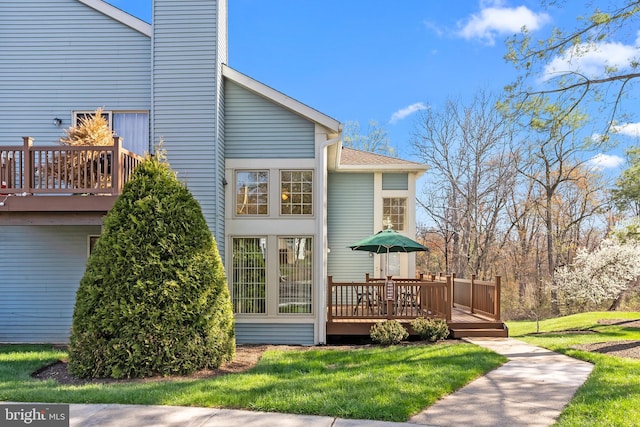 rear view of property featuring a yard and a deck