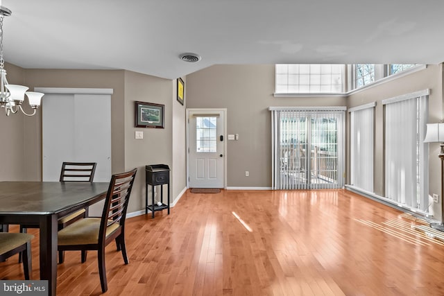 dining space with light wood-style flooring, an inviting chandelier, baseboards, and visible vents