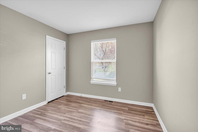 spare room with visible vents, baseboards, and wood finished floors