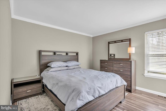 bedroom with visible vents, multiple windows, crown molding, and light wood-style flooring