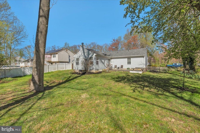 rear view of house featuring a yard, fence, and a chimney