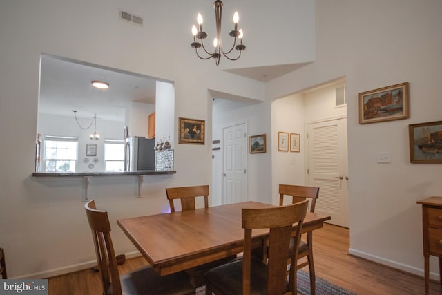 dining area featuring wood finished floors, visible vents, baseboards, and a notable chandelier