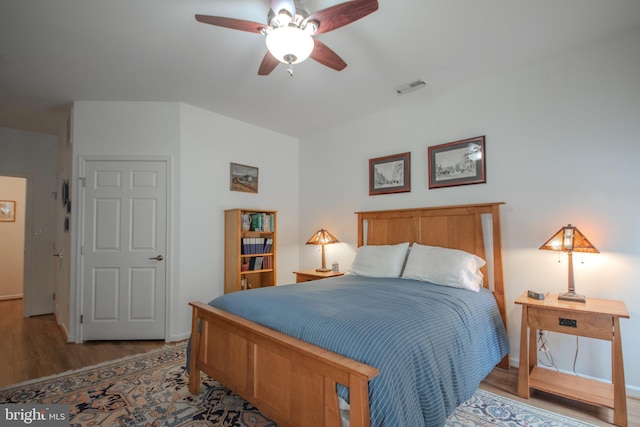 bedroom featuring wood finished floors, visible vents, baseboards, and ceiling fan