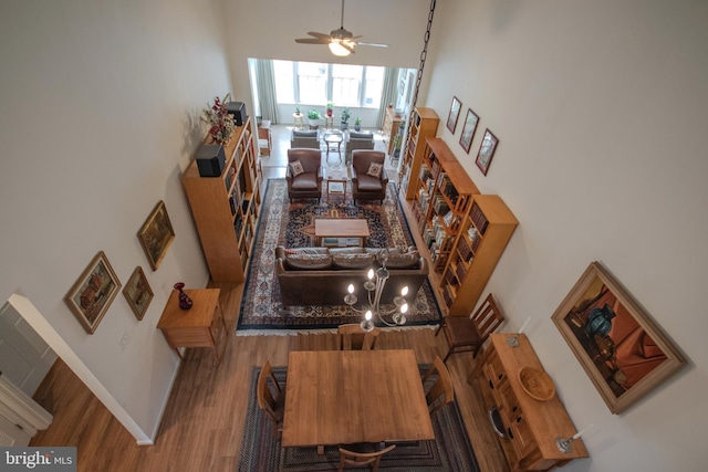 interior space featuring wood finished floors, a towering ceiling, baseboards, and ceiling fan