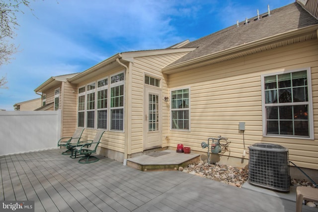 rear view of property featuring fence, roof with shingles, cooling unit, and a deck