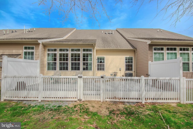 back of property with fence and a shingled roof
