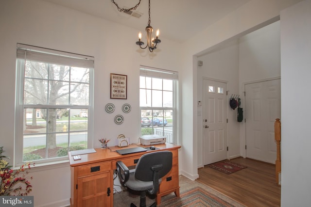 office space with light wood-type flooring, baseboards, and an inviting chandelier