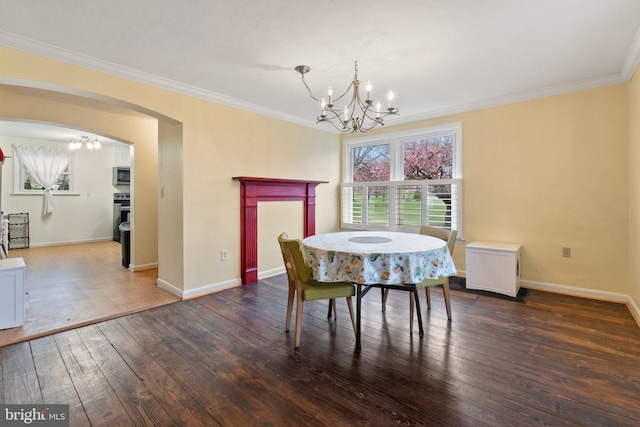 dining room with crown molding, arched walkways, a chandelier, and hardwood / wood-style flooring