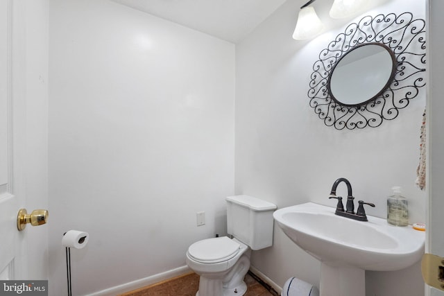 bathroom featuring baseboards, a sink, and toilet