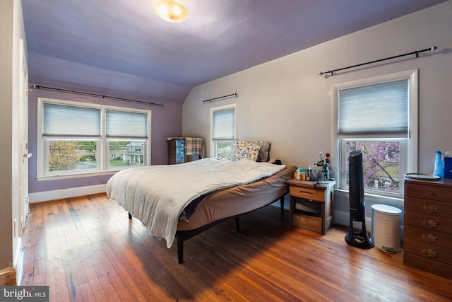 bedroom with wood-type flooring, baseboards, multiple windows, and vaulted ceiling