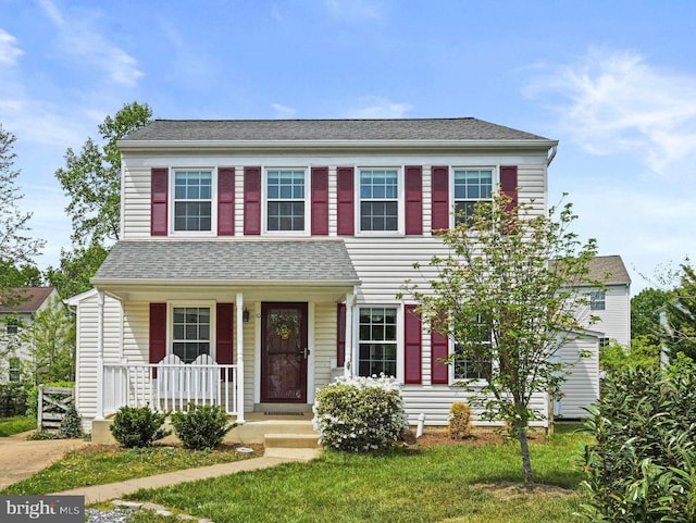colonial-style house with a porch and roof with shingles