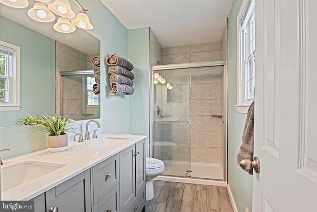 bathroom featuring toilet, a shower stall, a sink, and wood finished floors