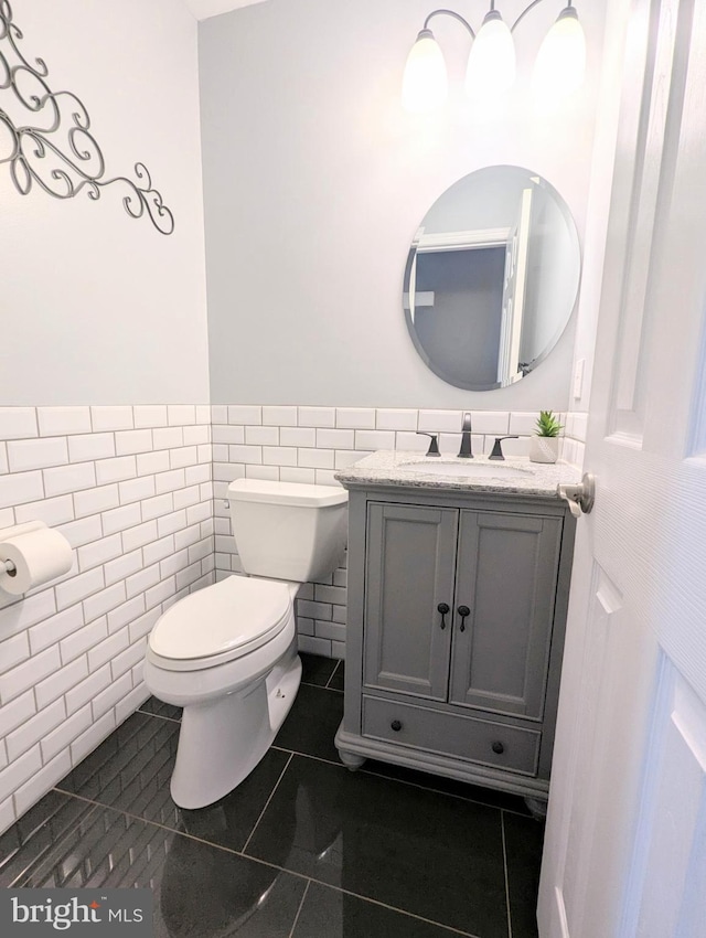 bathroom with tile walls, wainscoting, vanity, tile patterned floors, and toilet
