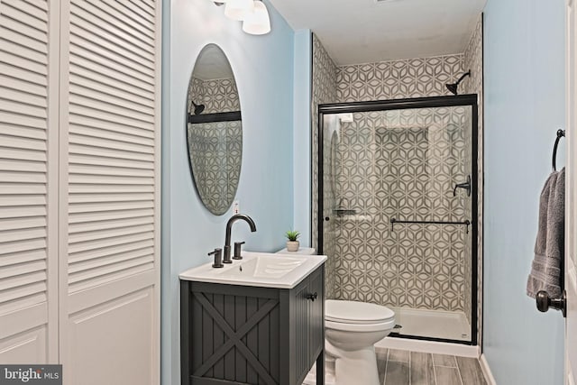 full bathroom with a closet, a stall shower, toilet, and vanity