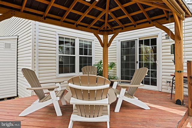 wooden terrace featuring a gazebo and outdoor dining space