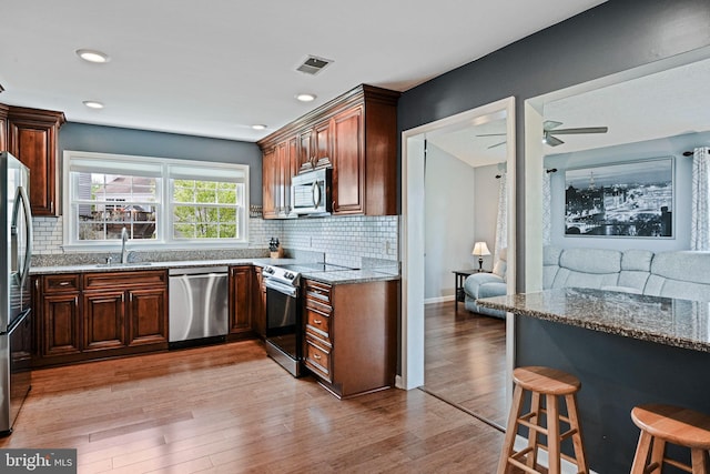 kitchen with visible vents, light wood-style floors, light stone counters, a sink, and stainless steel appliances
