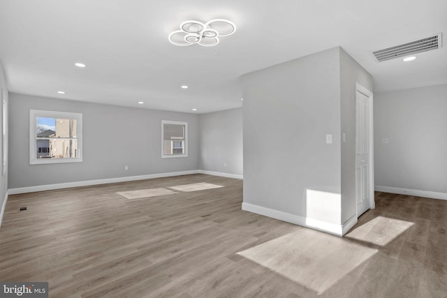 unfurnished living room with wood finished floors, baseboards, visible vents, and recessed lighting