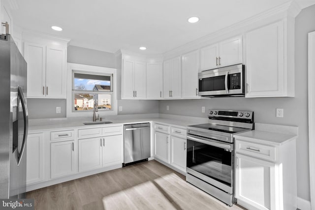 kitchen with light wood-type flooring, white cabinetry, appliances with stainless steel finishes, light countertops, and a sink