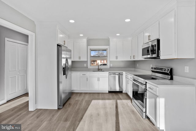 kitchen featuring light wood finished floors, a sink, white cabinetry, and stainless steel appliances