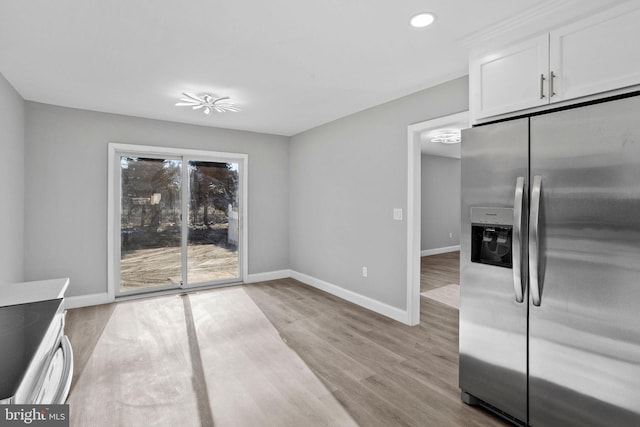 unfurnished dining area with baseboards, light wood-type flooring, and recessed lighting