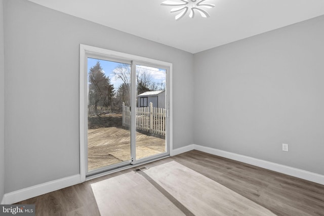 spare room featuring visible vents, baseboards, and wood finished floors