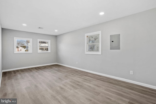 empty room featuring electric panel, baseboards, and wood finished floors