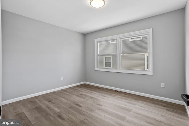 spare room featuring visible vents, baseboards, and wood finished floors